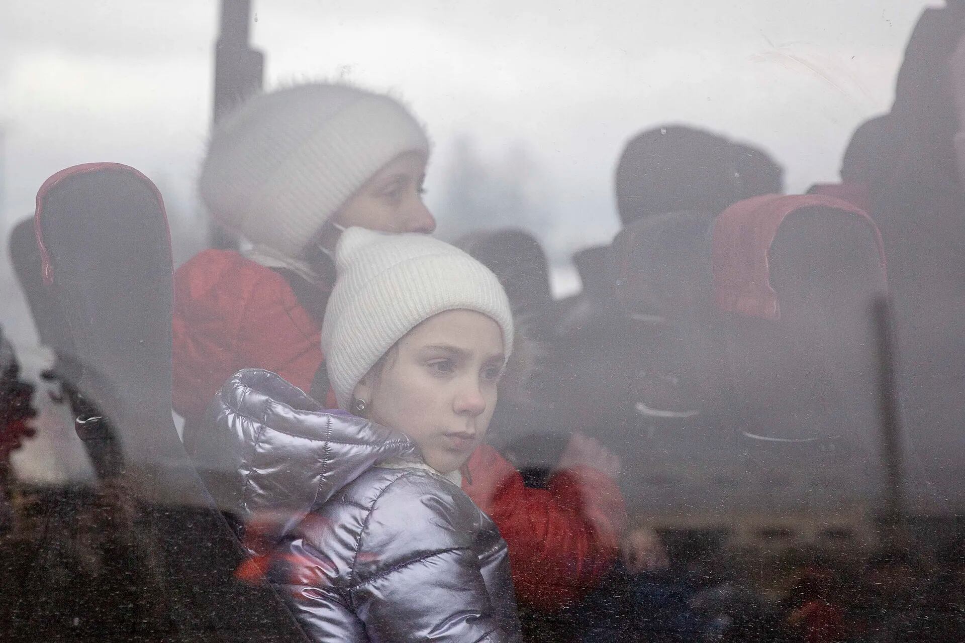 Una niña mira por la ventanilla de un autobús luego de huir de Ucrania hacia la frontera con Polonia