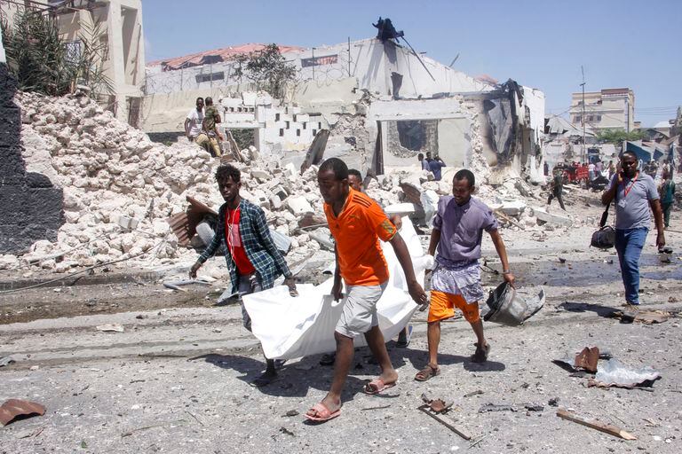 Rescatistas trasladan el cuerpo de un civil muerto en una explosión en Mogadiscio, Somalia el miércoles 12 de enero de 2022. Varias personas murieron o resultaron heridas el miércoles en una gran explosión ante el aeropuerto internacional de la capital somalí, según un trabajador de emergencias. (AP Foto/Farah Abdi Warsameh)