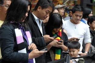 Una familia en Filipinas envía mensajes de texto desde sus  celulares. El uso extendido de dispositivos móviles e Internet transformaron la forma de comunicarse en todo el mundo