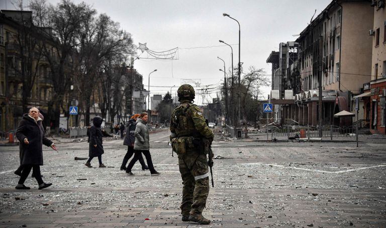 La gente pasa al lado de un soldado ruso en el centro de Mariupol el 12 de abril de 2022.