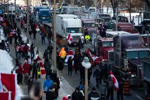 Personas caminan junto a camiones estacionados en la calle Wellington durante una manifestación contra las restricciones del COVID-19 en el Parlamento, en Ottawa, el sábado 29 de enero de 2022. (Justin Tang/The Canadian Press vía AP)