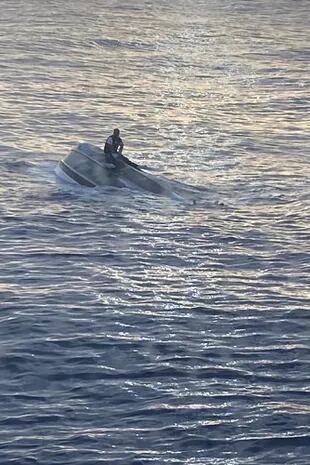 Fotografía divulgada por la sección Sureste de la Guardia Costera estadounidense donde se aprecia a un sobreviviente de un naufragio aferrado en un bote frente de la costa de Fort Pierce, a unos 240 kilómetros (150 millas) al norte de Miami, Florida (EE. UU). 