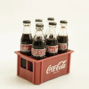 Cajón de botellitas en miniatura, 1985. Con diez tapitas de gaseosas de la línea Coca te llevabas una versión en miniatura con el logo en diferentes idiomas. Para tener el cajonicto, necesitabas otras diez tapitas. 