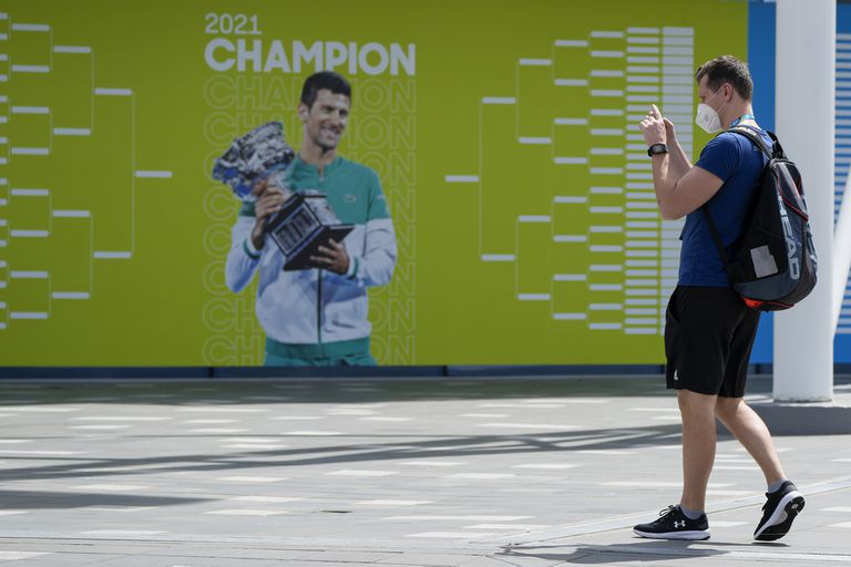 Un visitante se detiene para tomar una foto de una valla publicitaria con el campeón defensor,Novak Djokovic, antes del Abierto de Australia