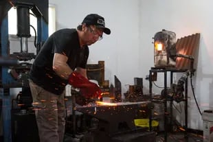 Con un martillo trabaja el acero para empezar a confeccionar la pieza.
