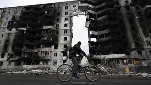 TOPSHOT - A cyclist passes by a destroyed building in the town of Borodianka, northwest of Kyiv, on April 6, 2022. - The Russian retreat last week has left clues of the battle waged to keep a grip on Borodianka, just 50 kilometres (30 miles) north-west of the Ukrainian capital Kyiv. (Photo by Genya SAVILOV / AFP)