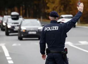 Un oficial de policía austriaco hace un gesto hacia los conductores de automóviles durante un control de tráfico en el Südring en Klagenfurt, Austria, el 15 de noviembre de 2021, al ser el primer país europeo en imponer un bloqueo a los no vacunados