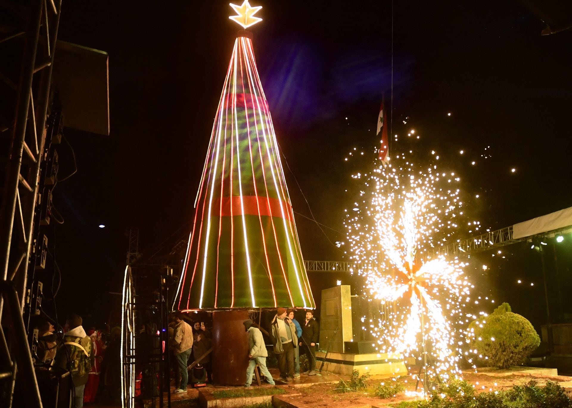La gente se reúne para celebrar el encendido de un árbol de Navidad gigante instalado entre el Eparca católico caldeo y la mezquita Al-Tawhid, en la ciudad de Alepo, en el norte de Siria