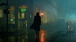 Neo caminando de manera icónica en una calle oscura