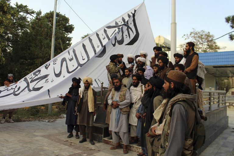 Milicianos talibanes posan para una foto mientras muestran su bandera en Ghazni