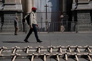 Un hombre camina junto a 30 cruces de madera en las escalinatas de la Catedral de Santiago para rendir homenaje a las víctimas del Covid-19 en Chile, el 25 de abril de 2021
