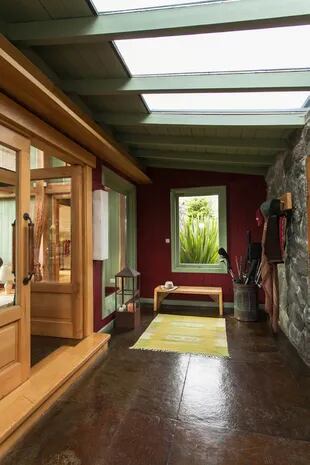 Con una pared de piedra, el hall frío da la bienvenida. Aquí, los colores están invertidos con respecto al resto de la casa: el bordó está en el fondo y el verde en las carpinterías.