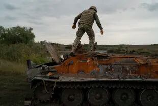 Un militar ucraniano se encuentra sobre un vehículo blindado ruso destruido en una zona retomada cerca de la frontera con Rusia en la región de Kharkiv, Ucrania, el sábado 17 de septiembre de 2022. (AP Photo/Leo Correa)