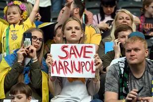 Una espectadora muestra un cartel con la frase "Salven Mariúpol" (en inglés) durante un partido de fútbol entre Borussia Moenchengladbach y la selección de Ucrania, en el Borussia Park, Monchengladbach, Alemania, el 11 de mayo de 2022. (Federico Gambarini/dpa via AP)
