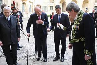 El ex rey de España Juan Carlos I es recibido por el escritor Maurizio Serra (a la derecha) para asistir a la ceremonia en París
