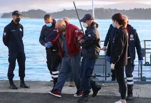 Un hombre ligeramente herido, ayudado por los guardacostas, llega al puerto de la isla de Corfú, en el noroeste de Grecia, tras la evacuación de un ferry, el viernes 18 de febrero de 2022.