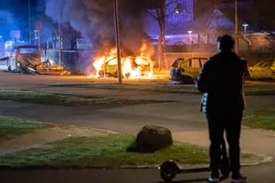 Un hombre observa autos incendiándose tras el estallido de protestas en Rosengard, distrito de Malmö, Suecia, la madrugada del lunes 18 de abril de 2022. (Johan Nilsson/TT vía AP)