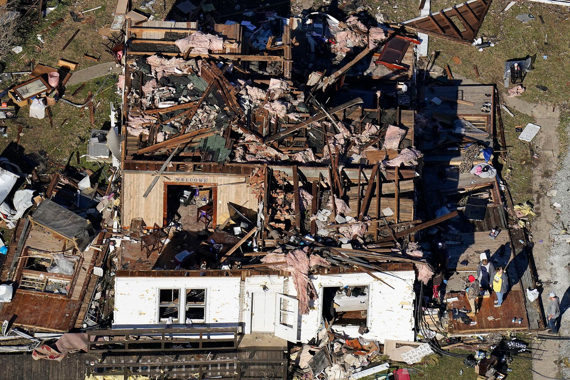 En esta foto aérea, la gente se para en el porche de una casa destruida a raíz de los tornados que arrasaron la región, en Dresde, Tennessee, el domingo 12 de diciembre de 2021