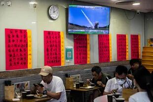 Una televisión en un restaurante en Hong Kong el 5 de agosto de 2022 muestra el lanzamiento de un misil durante los ejercicios militares que realiza China alrededor de la isla de Taiwán. (Photo by ISAAC LAWRENCE / AFP)
