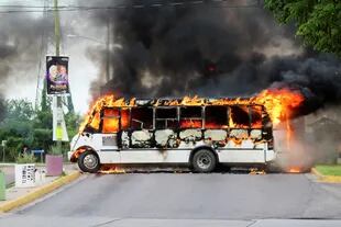 Un autobús incendiado, incendiado por pistoleros del cártel para bloquear una carretera.