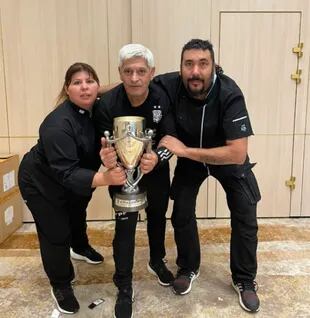 Diego Iacovone junto a Antonia Farías, también cocinera, y David, responsable del comedor. Los tres sostienen la copa que obtuvo el seleccionado por ganar la Finalíssima, el partido que enfretó al ganador de la Copa América con el ganador de la Copa de Europa