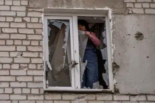 Una mujer coloca un plástico sobre los vidrios rotos de una ventana tras un ataque ruso en la víspera, en la zona residencial de Mikolaiv, Ucrania, el 29 de marzo de 2022. 