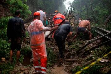 Bomberos, trabajadores municipales, oficiales de policía y voluntarios participan en una operación de rescate después de un deslizamiento de tierra