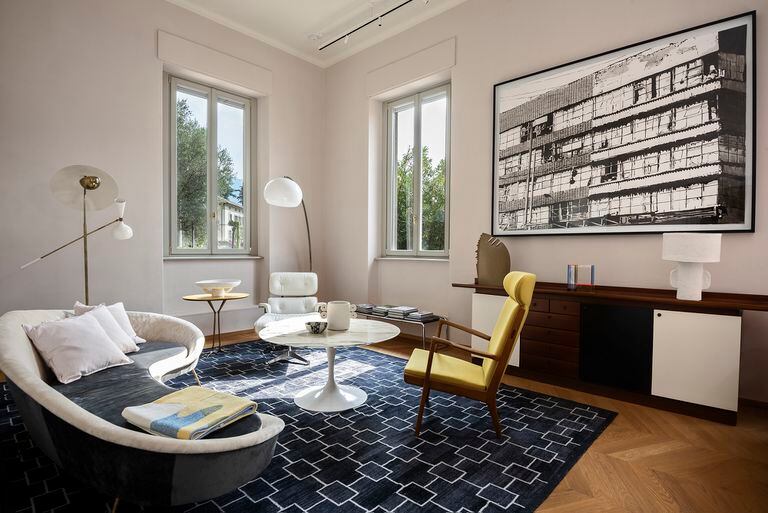 Fotos de un living con poltronas Eames en cuero blanco y de Hans Wegner, tapizada en color mostaza.