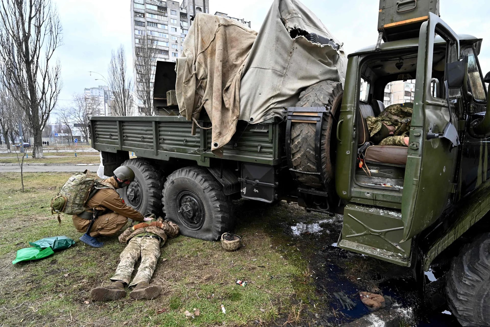 Unmico militar Ukraniano (izq.) Examina el cuerpo de una person que yase junto a un vehikulo despuis de que yl y los miembros de asalto recibieron disparo duranto un enfrantiranio de Kivi.