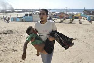Uno de los chicos alcanzados por el bombardeo israelí es llevado a cuestas ya sin vida