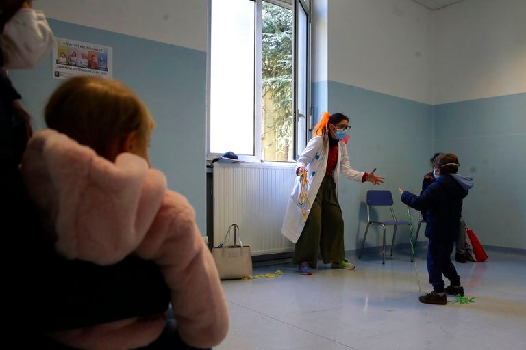 File - Venerdì 20 novembre 2020 Una ragazza in costume da clown intrattiene i bambini prima di ricevere un vaccino antinfluenzale in un ospedale militare a Milano, Italia.  (Foto AP / Luca Bruno, file)