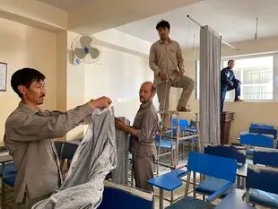 Hombres colocan una cortina para separar a los hombres de las mujeres en el aula