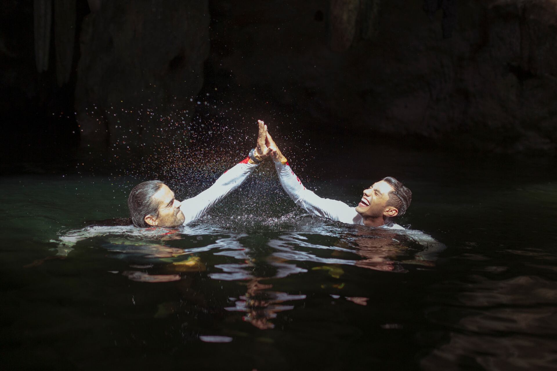 Orlando Duque y Jonathan Paredes celebran con un saludo luego de saltar en el Cenote Tsukán en Mérida, Yucatán