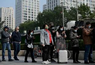 La gente espera en una fila para hacerse la prueba del coronavirus Covid-19 en una estación de recolección de ácido nucleico en Beijing el 25 de octubre de 2021