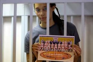 Brittney Griner sostiene una foto de su equipo mientras se encuentra dentro de una jaula de acusados antes de una vista judicial en Khimki, a las afueras de Moscú.