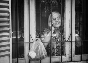 Una mujer de Mercedes, en la provincia de Buenos Aires, recibe en su ventana las compras realizadas por un grupo de voluntarios abocados a asistir a las personas mayores afectadas por las medidas de aislamiento