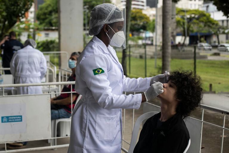 Un trabajador sanitario toma una muestra nasal para una prueba de COVID-19, el viernes 7 de enero de 2022, en un centro de pruebas instalado en una escuela de Río de Janeiro, Brasil. (AP Foto/Bruna Prado)