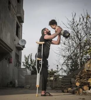 La fotografía premiada muestra a Munzir, que perdió la pierna derecha por un atentado mientras caminaba por un bazar en Idlib, Siria y a su hijo Mustafa que nació sin extremidades debido un trastorno congénito provocado por los medicamentos que tuvo que tomar su madre tras enfermarse por el gas sarín (Foto Mehmet Aslan)