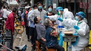 Médicos toman muestras de hisopos de los residentes para realizarles la prueba del coronavirus COVID-19 en una calle de Wuhan