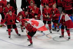 Marie-Philip Poulin de Canadá posa con su equipo tras vencer a Estados Unidos por la medalla de oro en el hockey femenino de los Juegos Olímpicos de Beijing el jueves 17 de febrero del 2022. (AP Foto/Jae C. Hong)