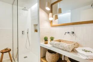 Baño en suite con espejo enmarcado hecho a medida, bacha de mármol (Tikamoon) y lámparas de cerámica diseñadas por Farré & Costa.