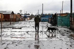 Un hombre camina por una calle fangosa en un sector pobre de Santiago el 29 de junio de 2020