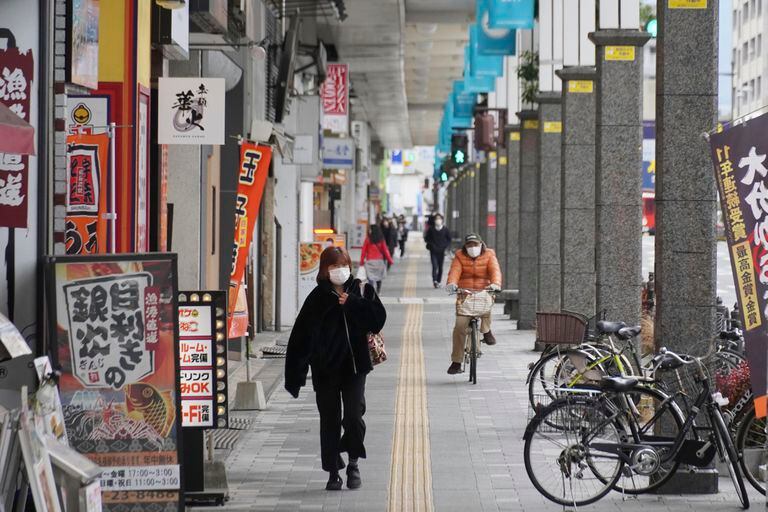 Varias personas, con mascarilla para protegerse del coronavirus, caminan por una calle en Iwakuni, en la prefectura de Yamaguchi, en el oeste de Japón, el 6 de enero de 2022. (Kyodo News vía AP)