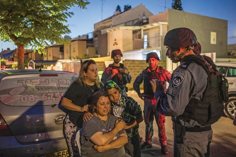Una familia acongojada habla con soldados israelíes en Ashkelon, luego de intensos bombardeos 