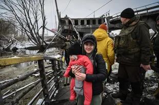 Los civiles cruzan un río en un puente volado en el frente norte de KyivÕs el 1 de marzo de 2022