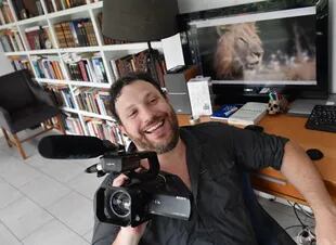 Santiago Oría sonríe en su casa. En su mano, la cámara que usa para filmar las recorridas del diputado Milei.