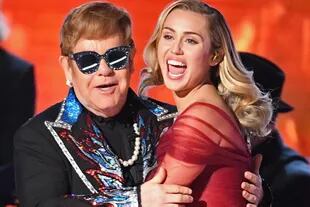 Elton John empezó a despedirse. El dueto de Sir Elton John y Miley Cirus conmovió a todos con un viaje en el tiempo al interpretar el clásico de 1971 “Tiny Dancer”. Anteojos y brillos para sir Elton John y sobrio vestido rojo para la niña traviesa del pop.