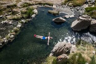 Relax en uno de los arroyos de agua termal que brota de las piedras de Aguas Calientes, en la base del volcán Domuyo.
