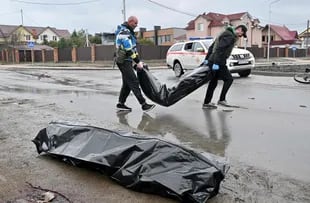 CAPTION ADDITION - Communal workers carry body bags in the town of Bucha, not far from the Ukrainian capital of Kyiv on April 3, 2022. US and NATO leaders voiced shock and horror at new evidence of atrocities against civilians in Ukraine, and warned that Russian troop movements away from Kyiv did not signal a withdrawal or end to the violence. - The Kremlin on April 4, 2022 rejected accusations that Russian forces were responsible for killing civilians near Kyiv. "We categorically reject all allegations," Kremlin spokesman Dmitry Peskov told journalists. (Photo by Sergei SUPINSKY / AFP)