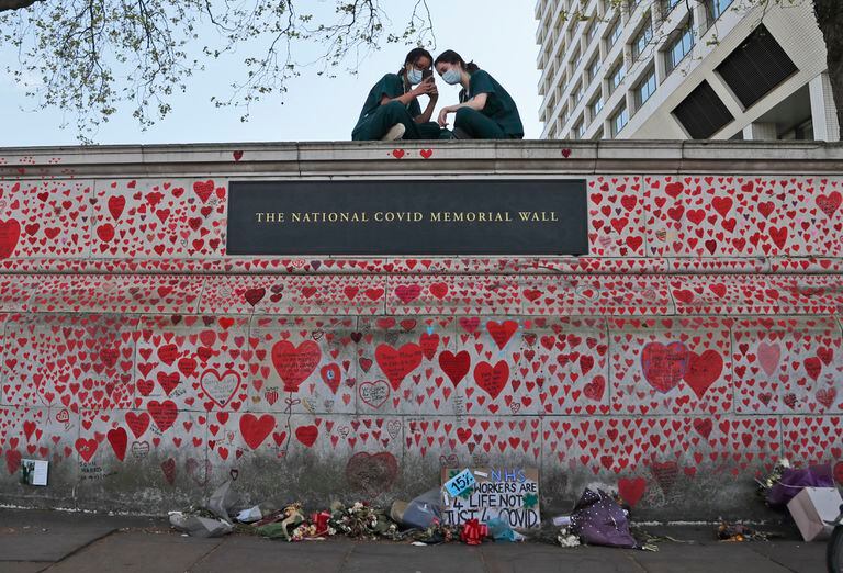 Enfermeras del Hospital St. Thomas están sentadas en el monumento nacional al COVID-19 en Londres, el 27 de abril de 2021. (AP Foto/Frank Augstein, file)